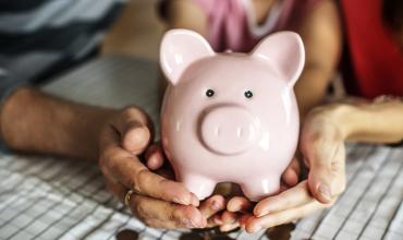 Two hands holding a piggy bank