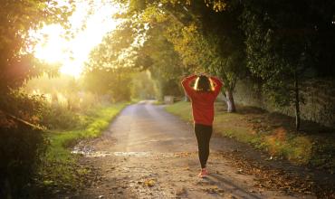 Woman walking on a greenway with hands on her head