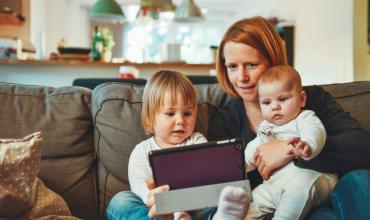 mom and two kids looking at a tablet