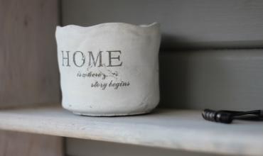 A ceramic vase on a shelf that says HOME on it