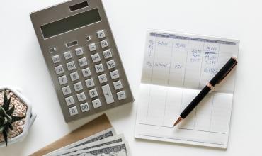checkbook with pen and calculator on white desk