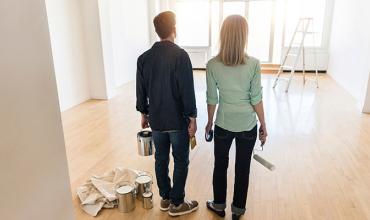 two people with painting supplies standing in a living room