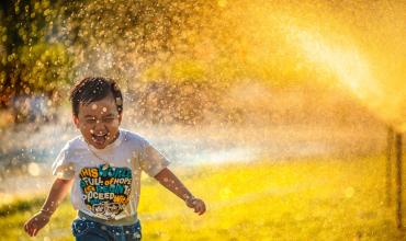 A little boy running through the sprinklers on a sunny day