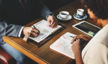 two people sitting at a table with notebooks