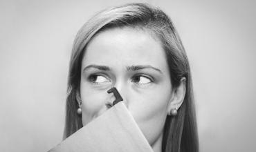 A woman holding a folder in front of her face 