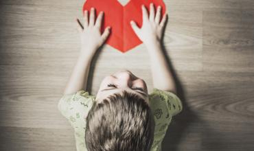 a kid with a red paper heart