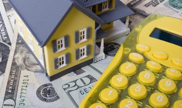 A toy house and a yellow calculator on a table