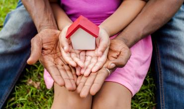 A father and daughter holding a little house in their hands