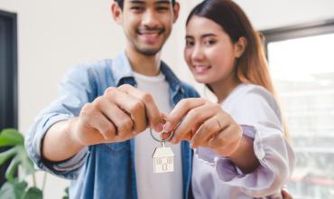 Two people holding up keys to their new home