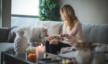 A woman in a sweater in her home with a dog