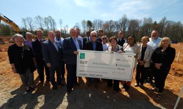 Group of people holding up a large check