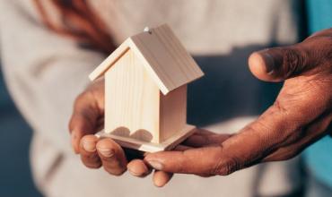 Hands holding a small wooden house