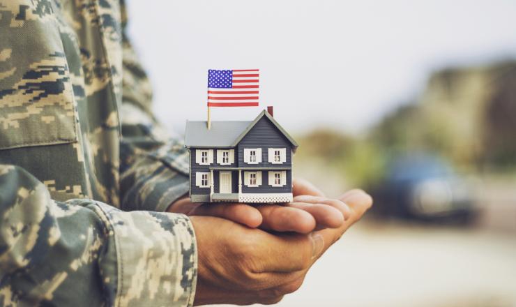 A veteran holding a mini house in his hands with an American flag on it
