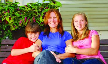 a smiling mother with her children, sitting on a bench