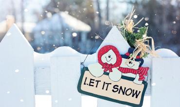 A sign that says Let it Snow on a white fence