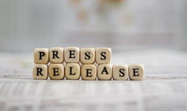 Lettered blocks stacked to say press release on a white table