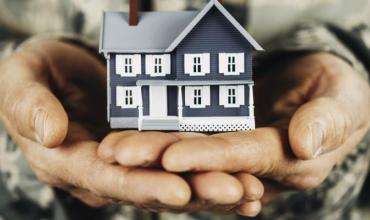 Military person holding a house in their hands