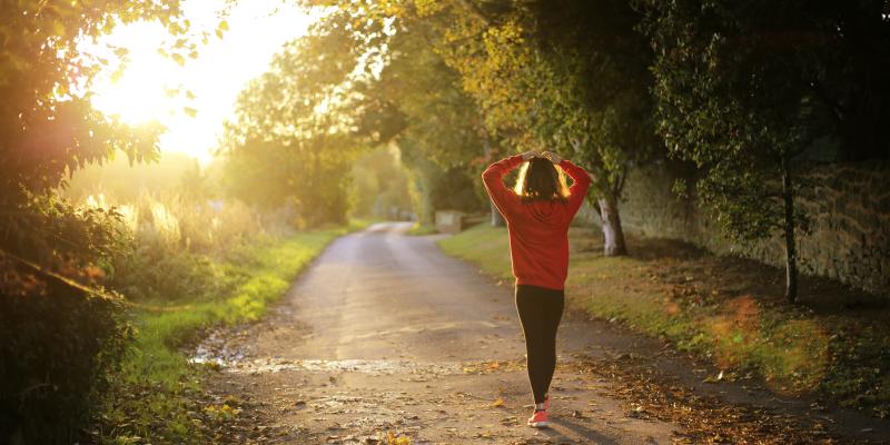 Woman walking on a greenway with hands on her head