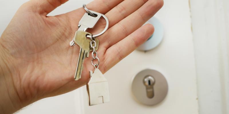 A hand holding keys in front of a door