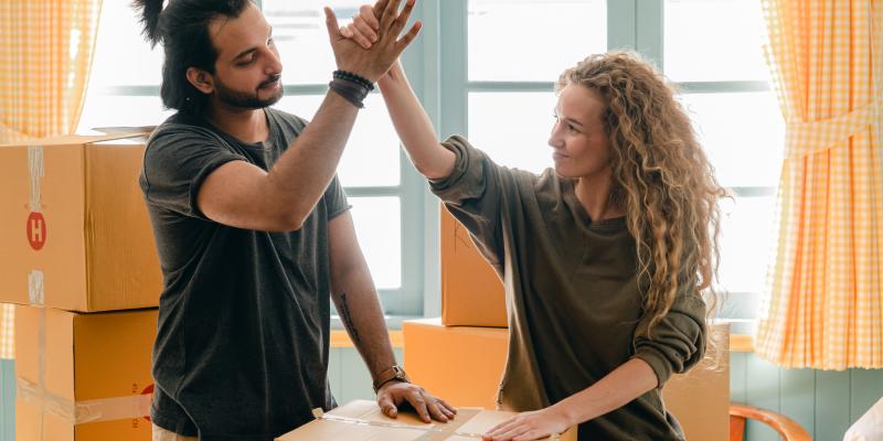 New homeowners high fiving amongst boxes in their new home