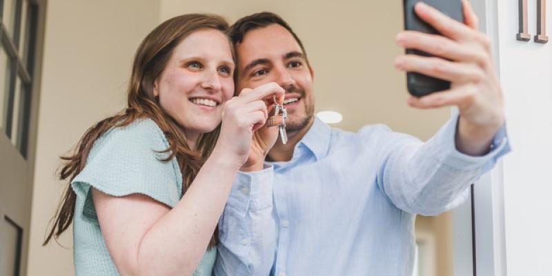 New homeowners taking a selfie holding up a key to their new home