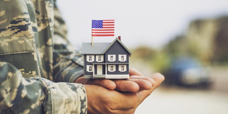 A veteran holding a mini house in his hands with an American flag on it
