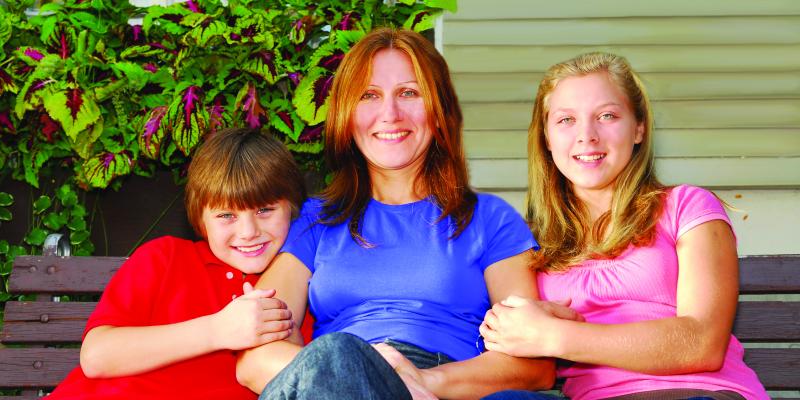 a smiling mother with her children, sitting on a bench