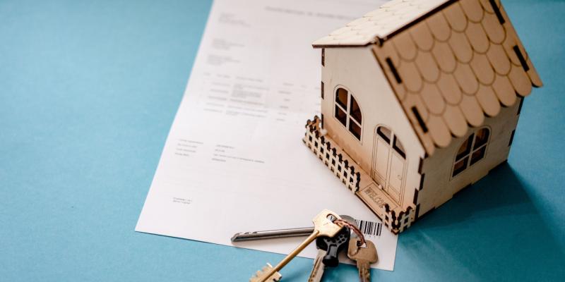 A small wooden house on top of a piece of paper with house keys next to it