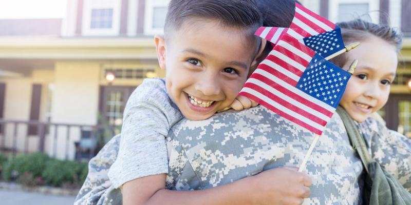 Veteran Homelessness is Decreasing in North Carolina A child holding the US flag being held by their parent in military uniform